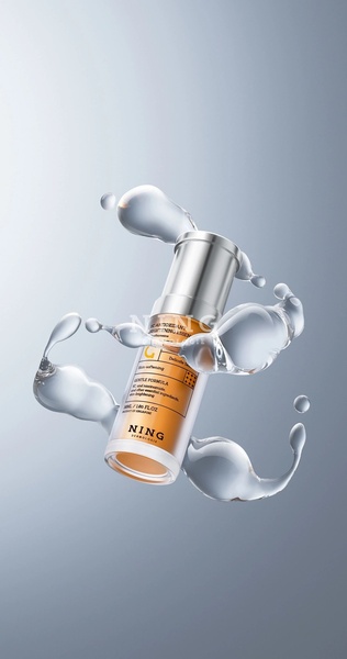 A high-end, studio-style product shot featuring a brightening essence bottle surrounded by suspended, clean water splashes against a gradient grey background.